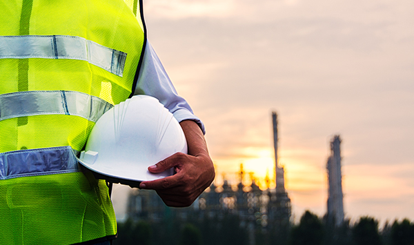 Safety officer holding hard hat with Petrochemical plant is background in construction site